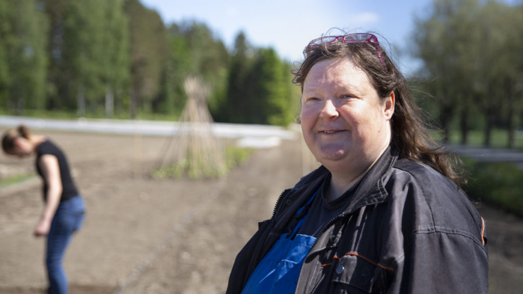 Kirstiina Myllymäki seisoo työvaatteissa aurinkoisella pellolla.