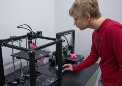 Opiskelija ohjaa 3D-tulostinta.
