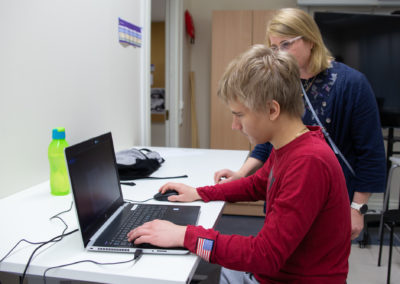 Opiskelija näyttää opettajalle työtä kannettavalta tietokoneelta.