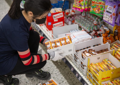 Merkonomiopiskelija hyllyttämässä karkkipatukoita supermarketissa.