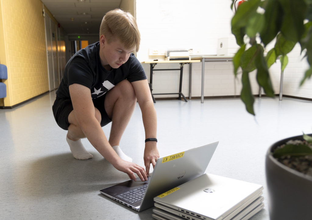 Nuori mies käyttää lattialla olevaa tietokonetta