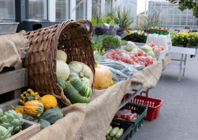 Vihanneksia ja juureksia esillä myyntipöydillä rakennuksen edessä ulkona.