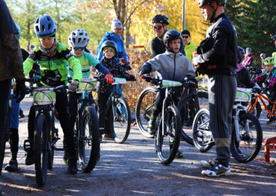 Maastopyöräilykisojen lasten luokan poikia valmiina lähtöviivalla ja isä ohjeistamassa.