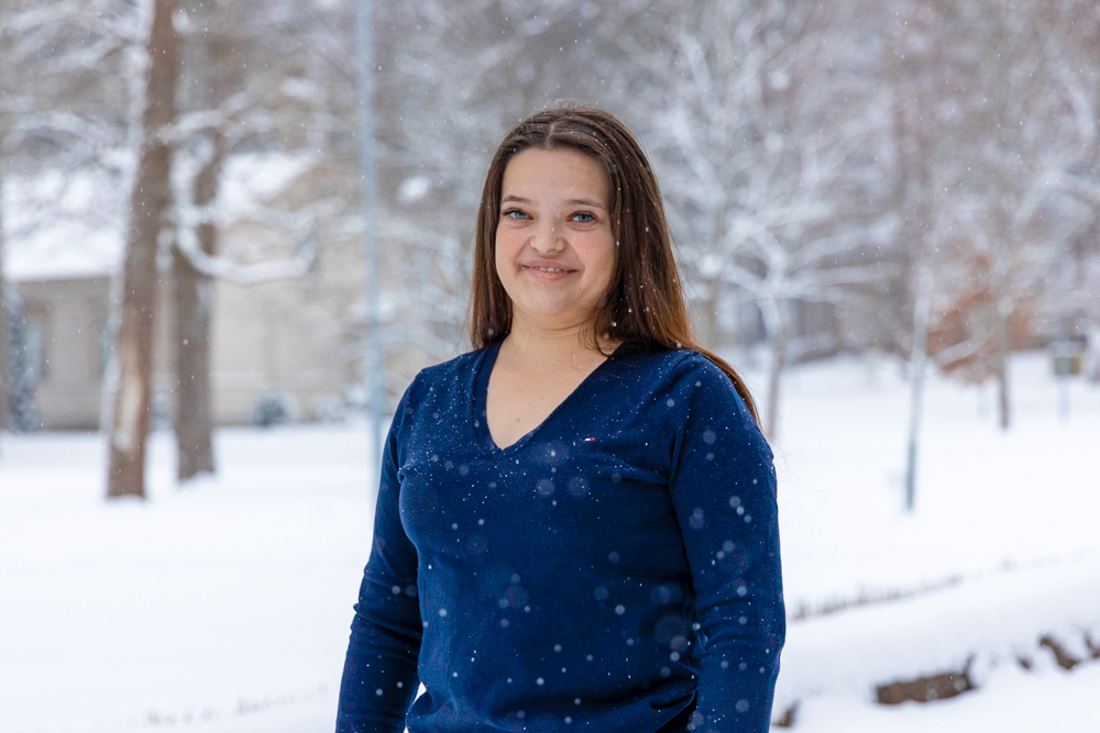 Valmistunut opiskelija Janika Ahola hymyilee kameralle lumisessa maisemassa.