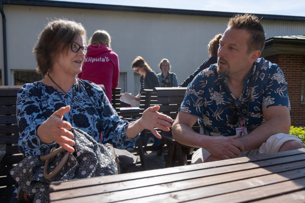 Mari Pirttiniemi ja Jusa Saarela keskustelemassa pöydän äärellä.