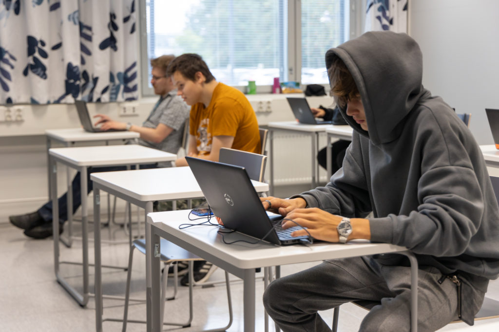 Opiskelijoita luokassa kannettavien tietokoneiden äärellä.