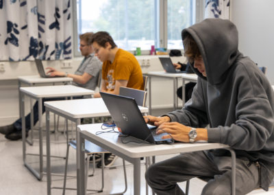 Opiskelijoita luokassa kannettavien tietokoneiden äärellä.