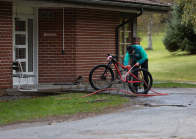 Pyöräilijä pesee polkypyöräänsä pihalla.